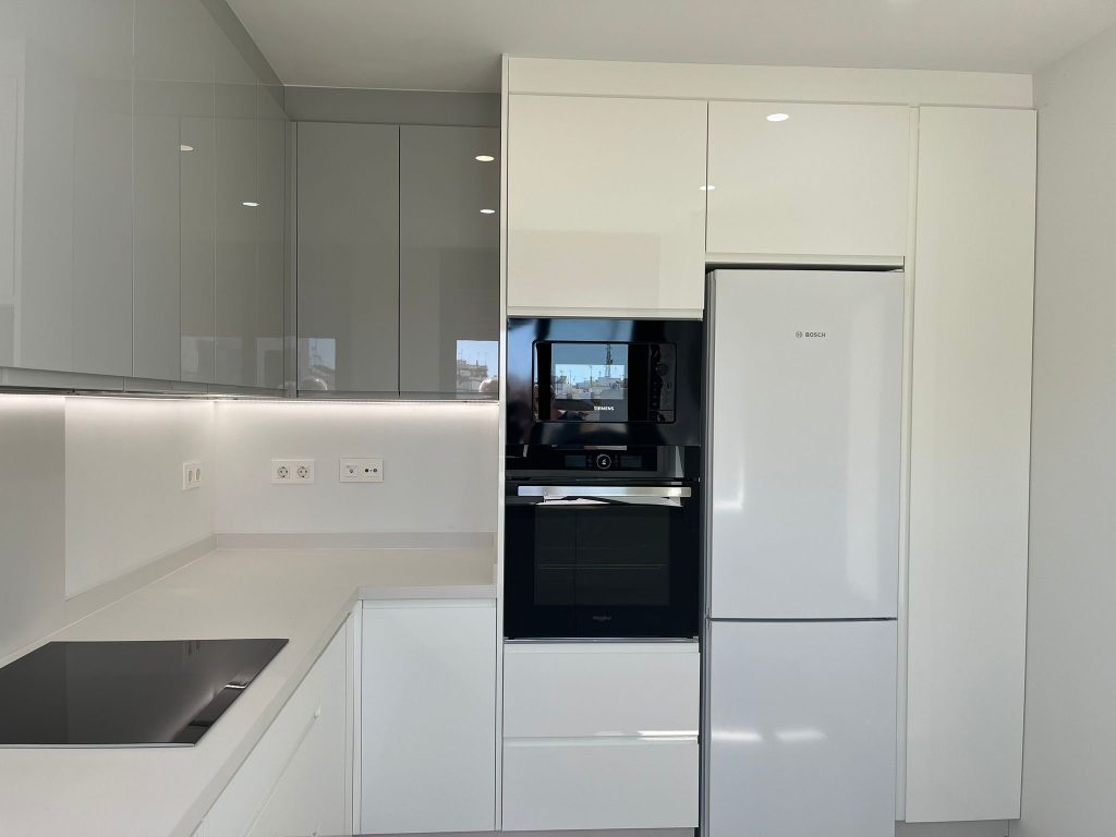 Cocina con puertas finger-pull blanco/ gris nube brillo, con encimera en Dekton Mod. Uyuni Chromica